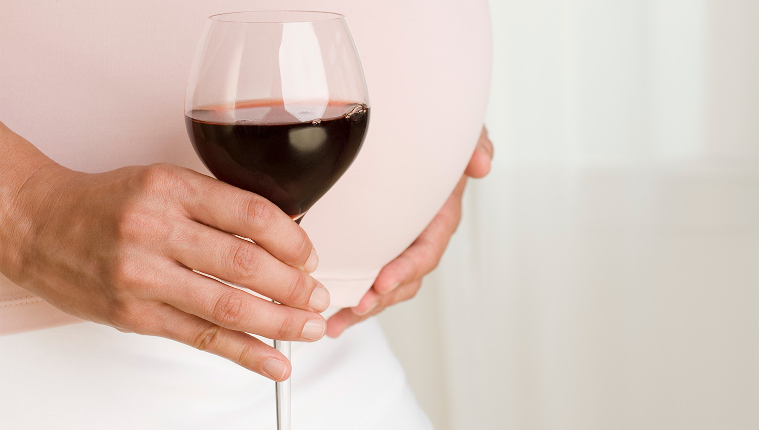 Una mujer embarazada con una copa de vino