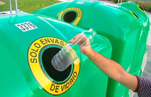 Reciclando una botella en un contenedor de reciclaje de vidrio