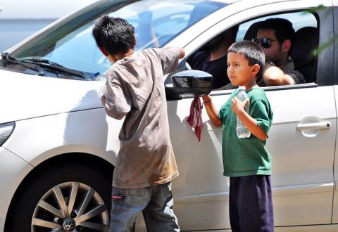 Dos niños trabajando limpiando coches