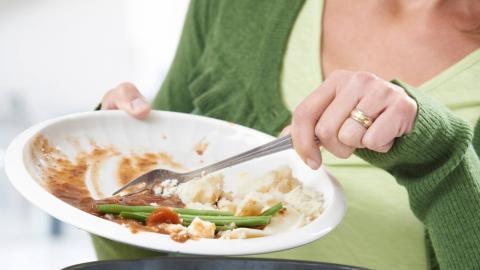 Una mujer tirando restos de comida a la basura