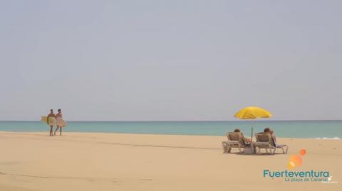 Playa de Fuerteventura con dos surferos y dos hamacas