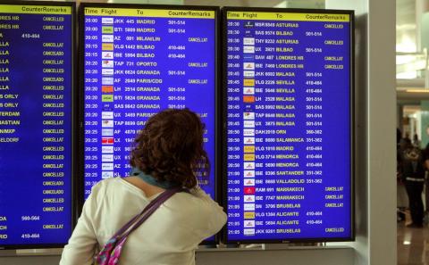 Una mujer delante de un panel informativo de un aeropuerto