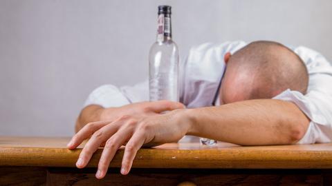 Un hombre dormido con una botella de alcohol