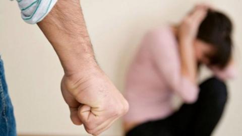 Puño de un hombre y una mujer acurrucada en el suelo